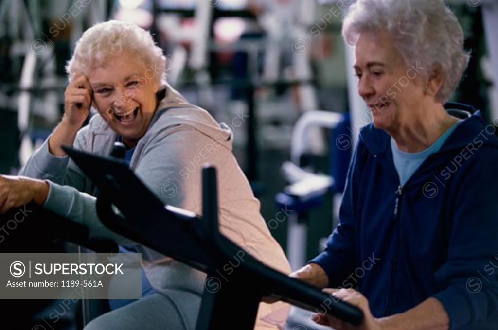 Stock Photo: 1189-561A Two senior women working on exercise machines at a gym