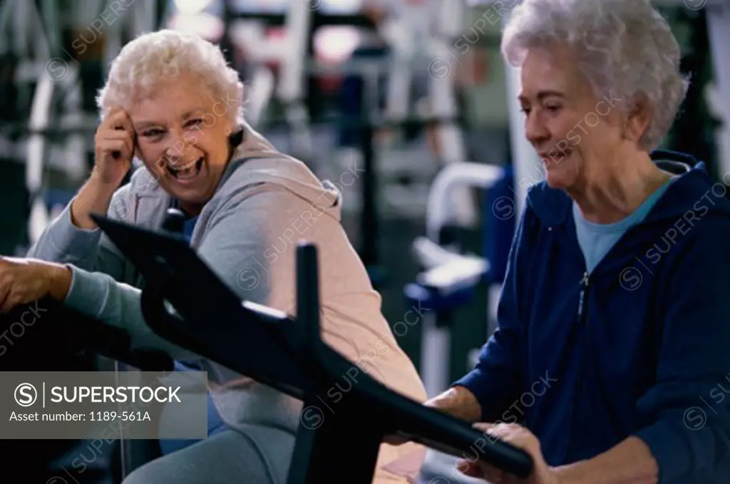 Two senior women working on exercise machines at a gym