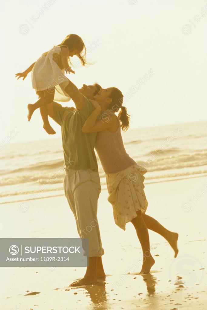 Stock Photo: 1189R-2814 Father and mother playing with their daughter on the beach