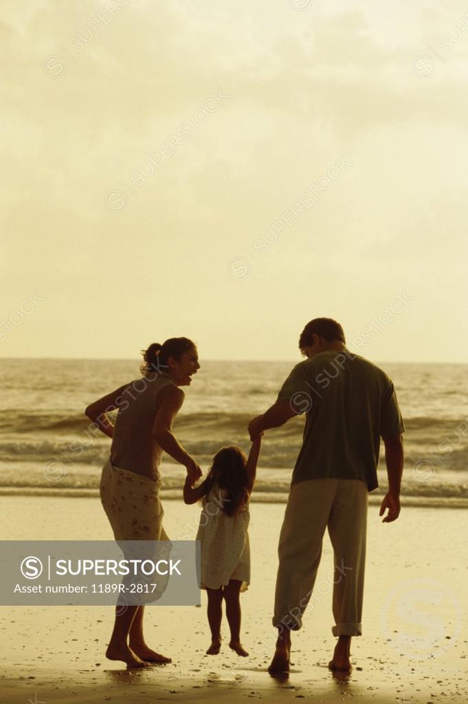 Stock Photo: 1189R-2817 Rear view of a father and mother with their daughter on the beach