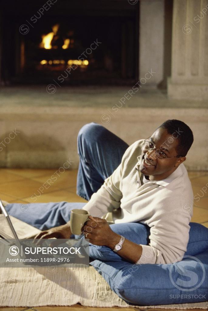 Stock Photo: 1189R-2976 Portrait of a young man working on a laptop holding a mug of coffee