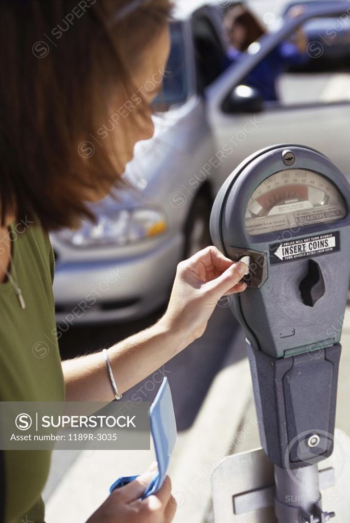 Stock Photo: 1189R-3035 Side profile of a young woman feeding an expired parking meter