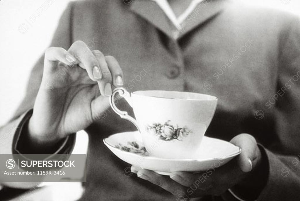 Stock Photo: 1189R-3416 Close-up of a woman's hand lifting a teacup from a saucer
