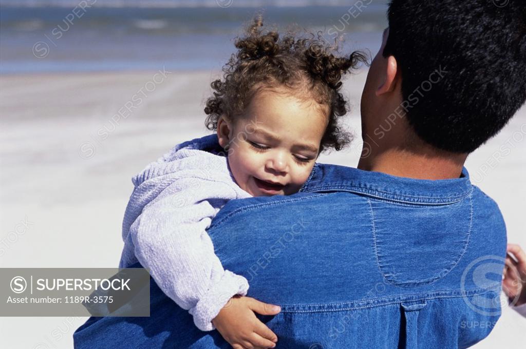 Stock Photo: 1189R-3575 Father carrying his daughter on the beach