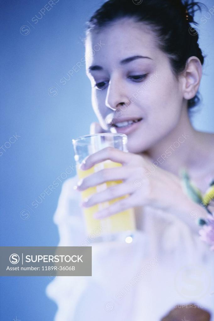Stock Photo: 1189R-3606B Young woman holding a glass of orange juice