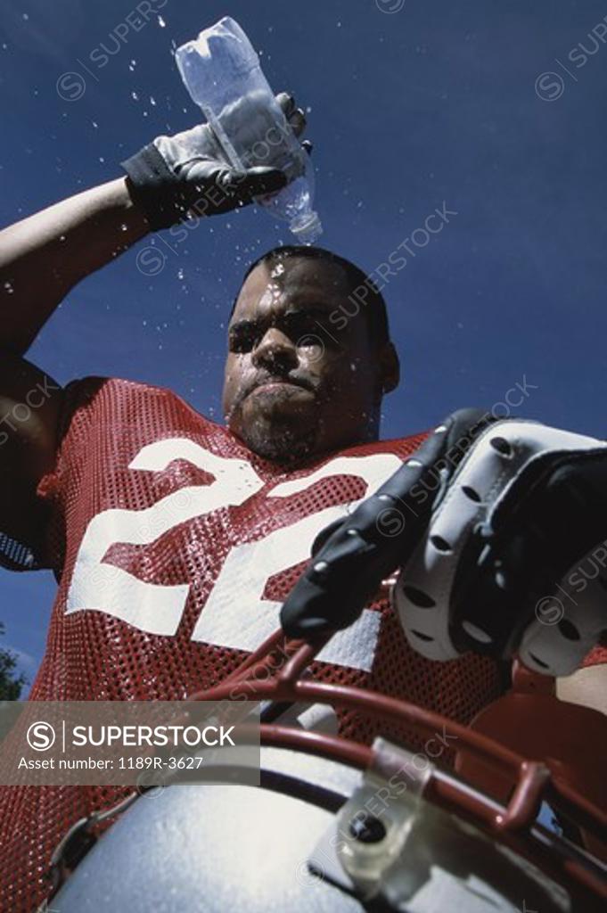 Stock Photo: 1189R-3627 Low angle view of an American football player pouring water on his head