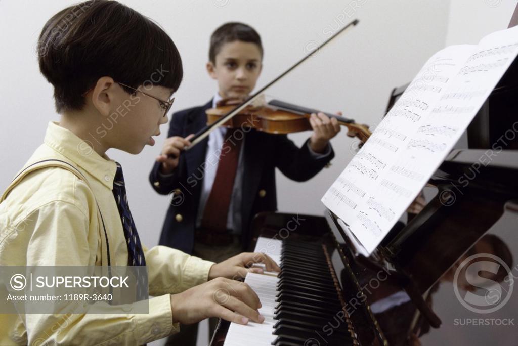 Stock Photo: 1189R-3640 Boy playing the piano and another playing the violin