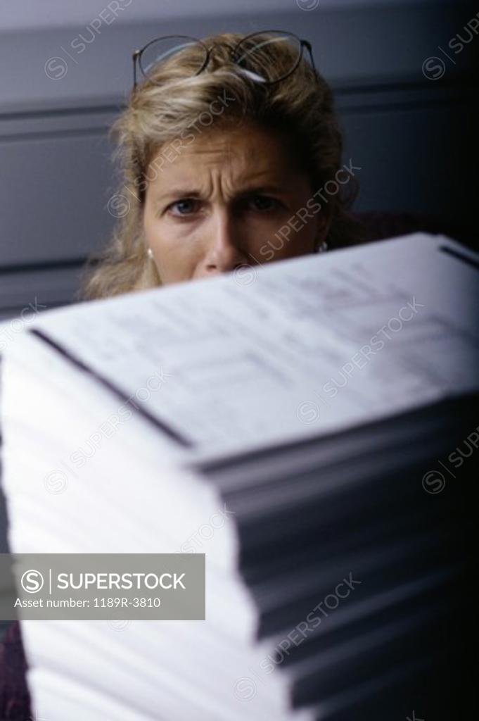 Stock Photo: 1189R-3810 Portrait of a businesswoman behind a stack of paper