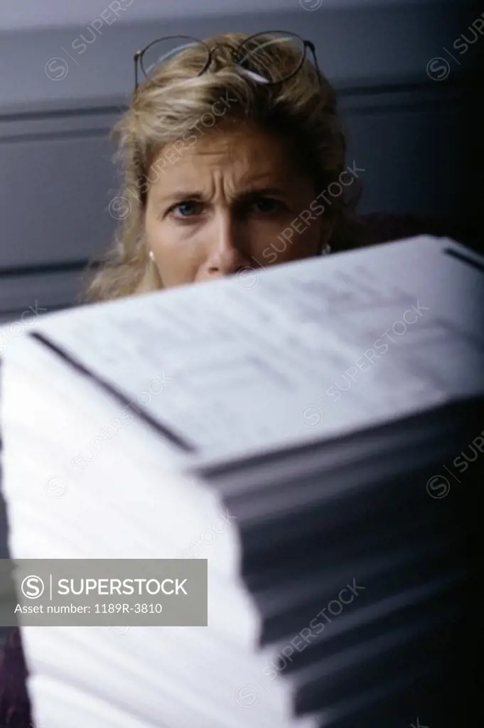 Portrait of a businesswoman behind a stack of paper