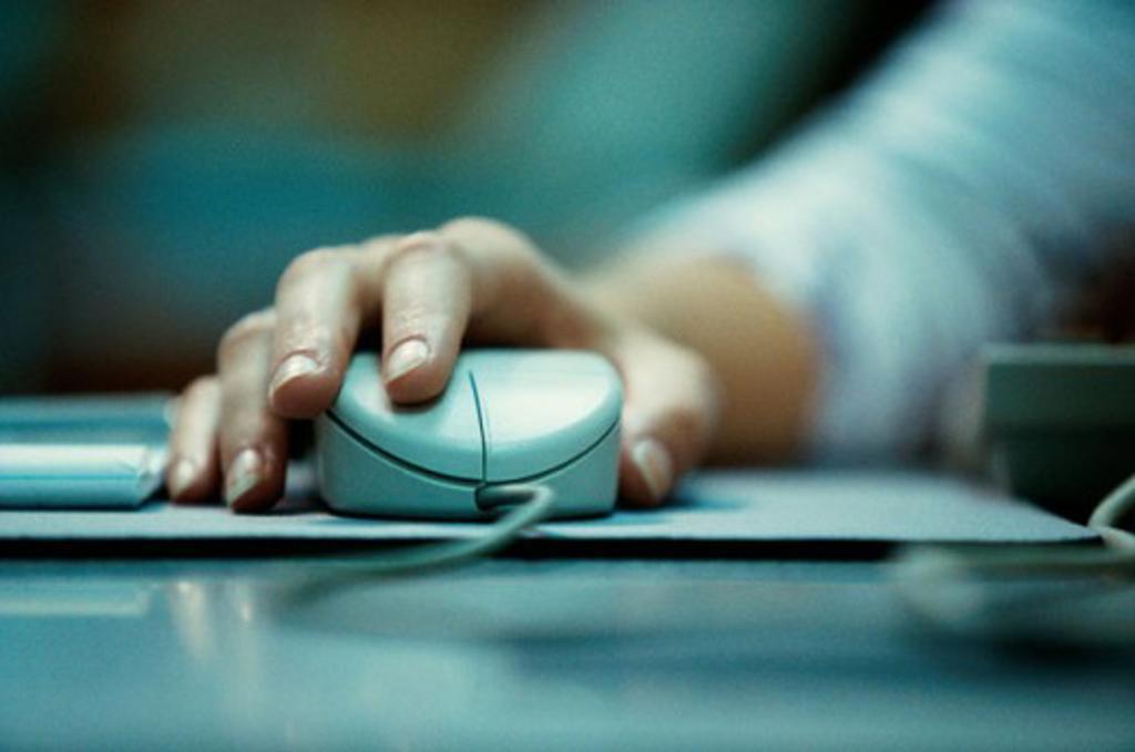 Close-up of a person's hand holding a computer mouse