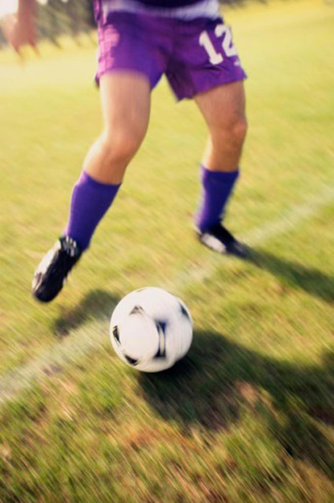 Low section view of a soccer player playing with a soccer ball