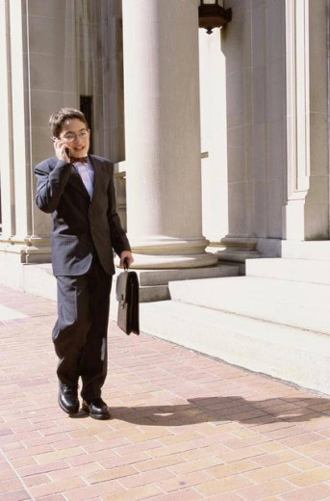 Boy wearing a business suit talking on a mobile phone