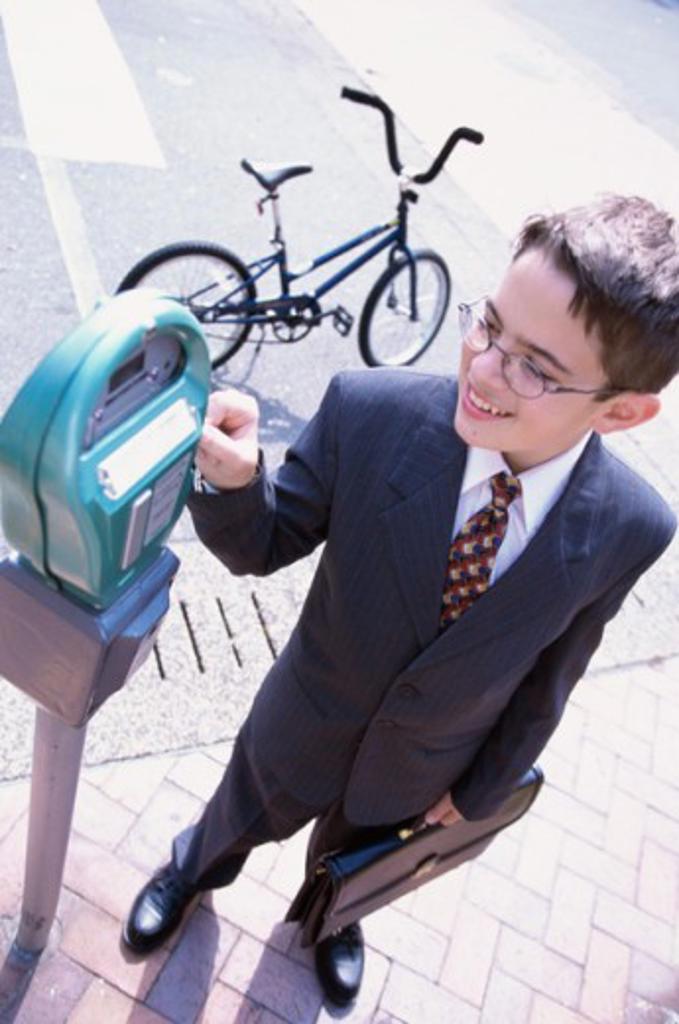 High angle view of a boy wearing a business suit operating a parking meter