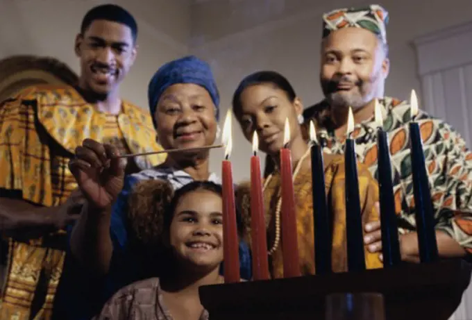 Close-up of a family standing behind a lit Mishumaa Saba to celebrate Kwanzaa