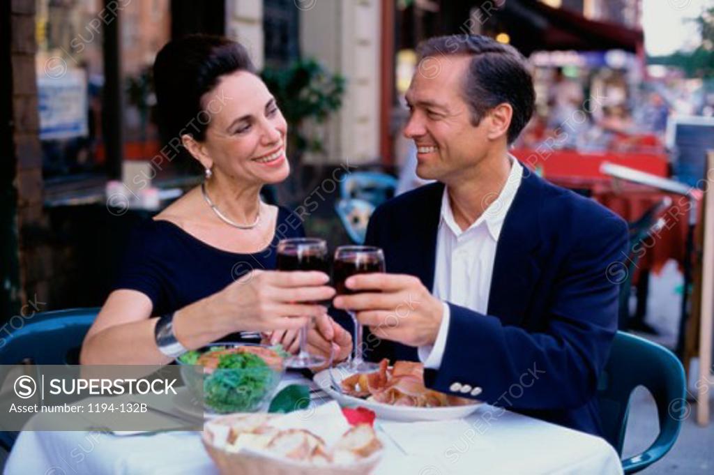 Stock Photo: 1194-132B Mid adult couple sitting together toasting at a restaurant