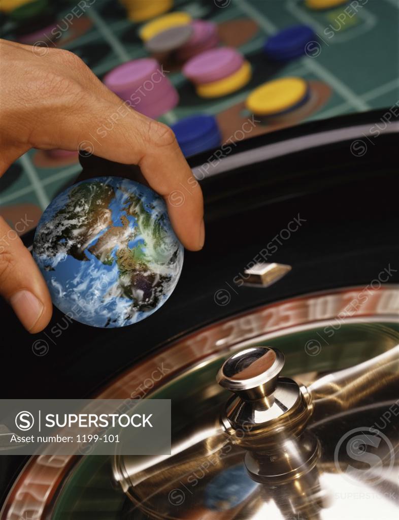 Stock Photo: 1199-101 Close-up of a person's hand holding a globe over a roulette wheel