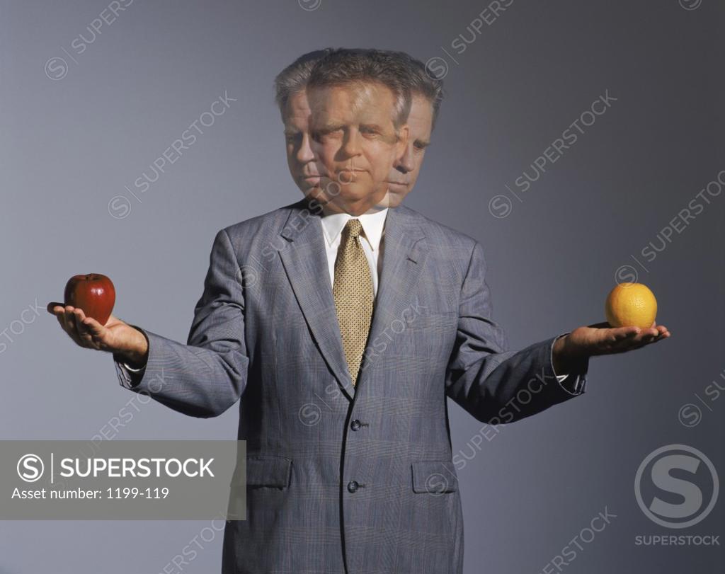 Stock Photo: 1199-119 Businessman holding an apple and an orange