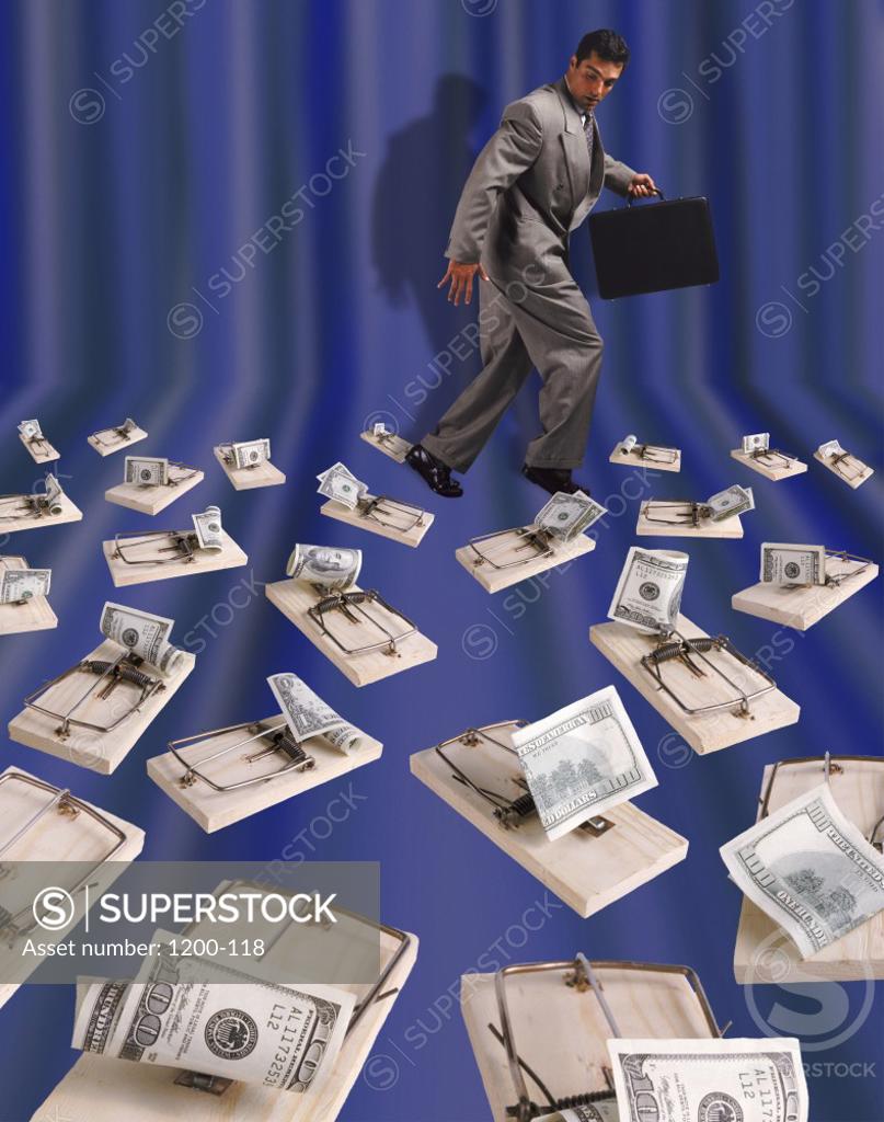 Stock Photo: 1200-118 Side profile of a businessman holding a briefcase walking amongst mousetraps with American dollar bills