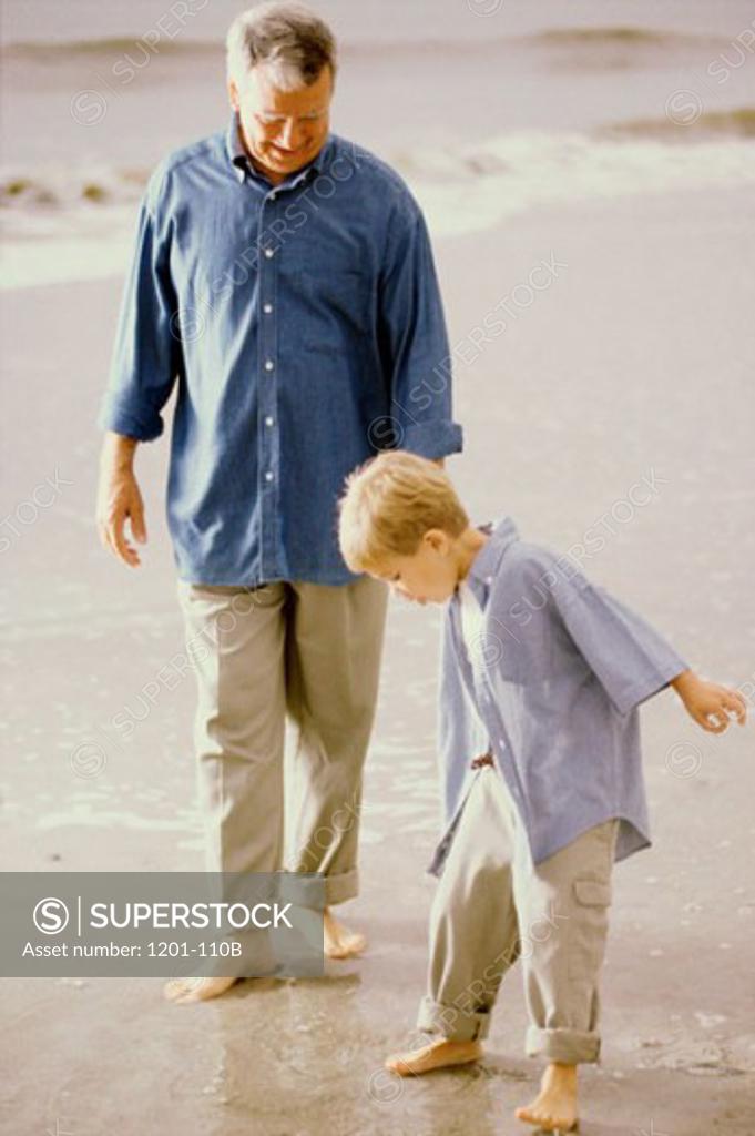 Stock Photo: 1201-110B Senior man walking with his grandson on the beach