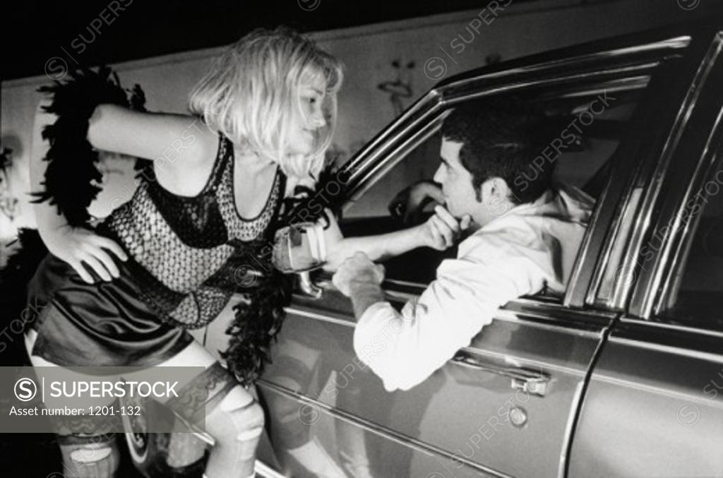 Stock Photo: 1201-132 Prostitute talking to a young man sitting in a car