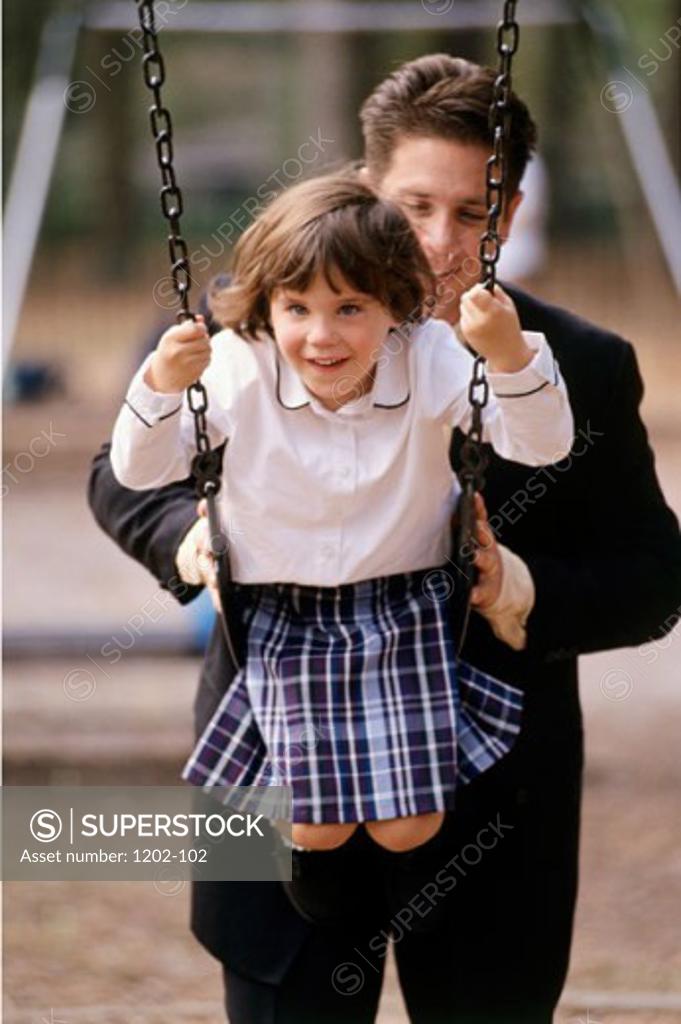 Stock Photo: 1202-102 Father pushing his daughter on a swing