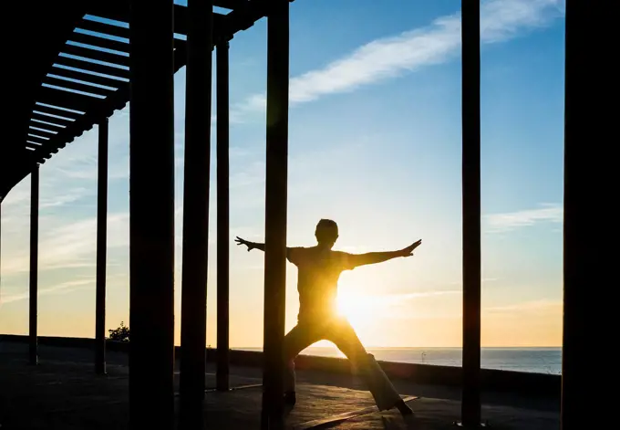 Las Palmas, Gran Canaria, Canary Islands, Spain, Man performing Tai Chi overlooking the Atlantic Ocean at sunrise.