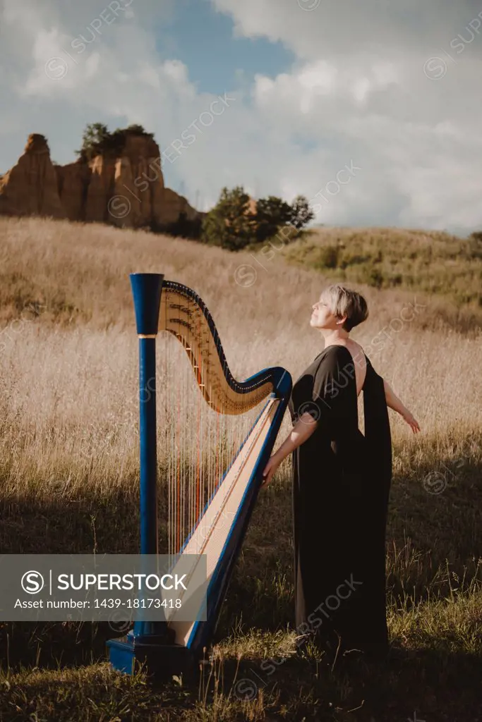 Italy, Tuscany, Firenze, Woman standing in field with harp