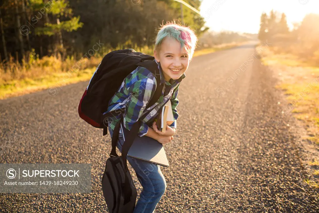 Canada, Ontario, Smiling boy (8-9) with books on rural road at sunset