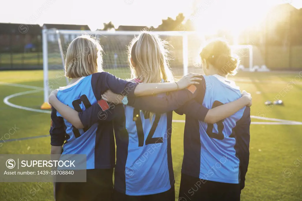 UK, Rear view of female soccer players embracing in field