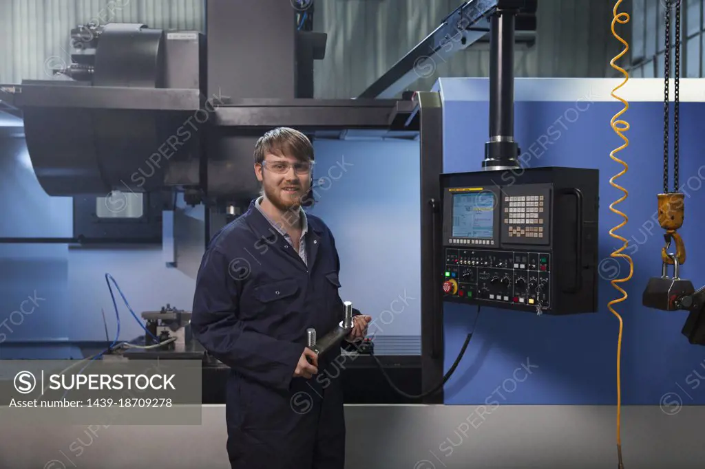 Apprentice holding a u-bolt strap in front of CNC machine