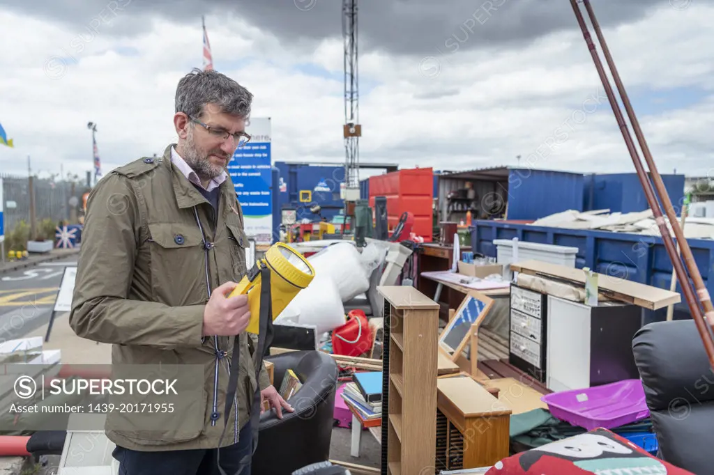 UK, Grimsby, Man holding flashlight at recycling center