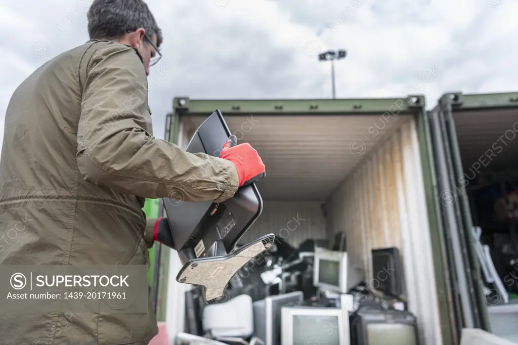 UK, Grimsby, Man holding old computer monitor at recycling center