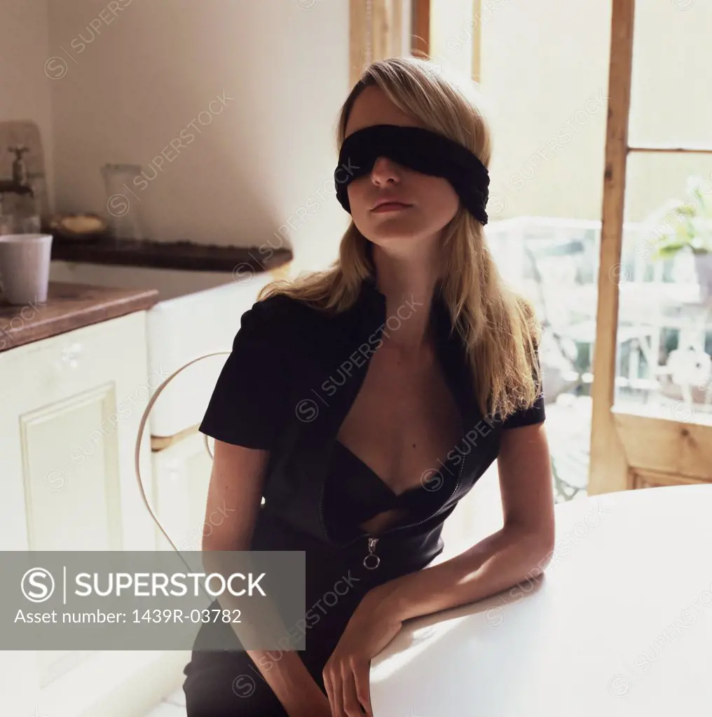 blindfolded woman sitting at a table - SuperStock