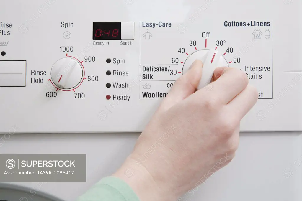 Person turning dial on washing machine