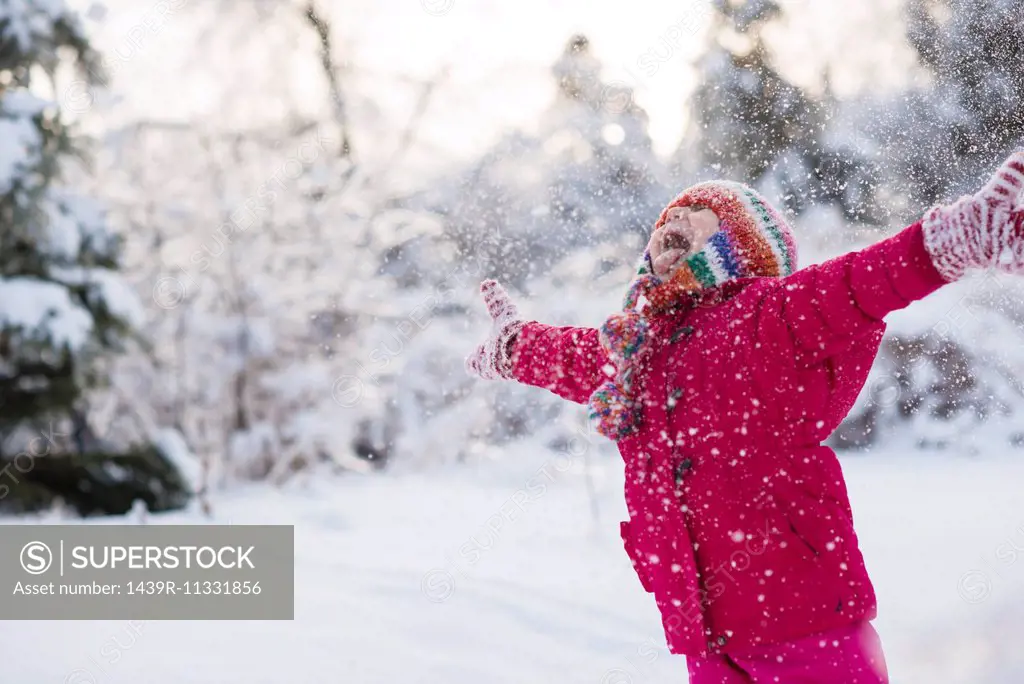 Young girl shouting and throwing snow mid air