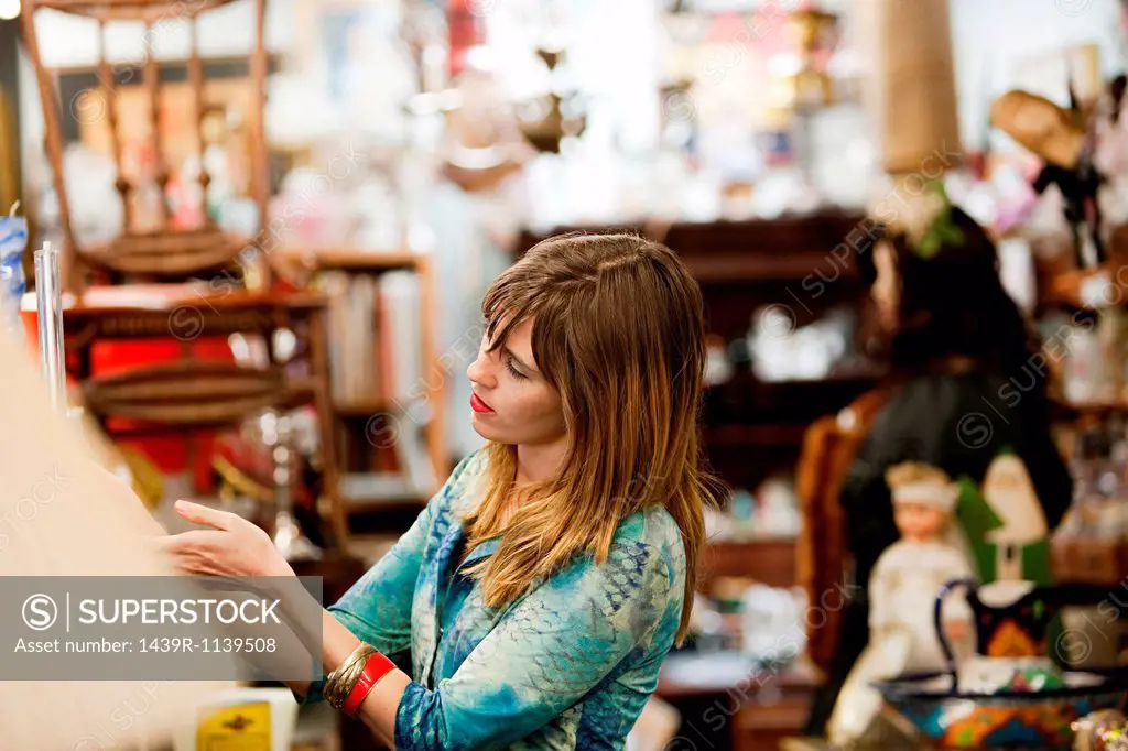 Woman inspecting items for sale in antiques shop
