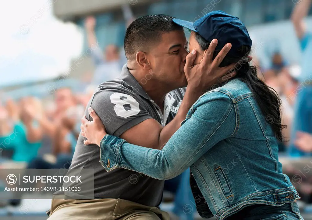 Couple kissing at sports game