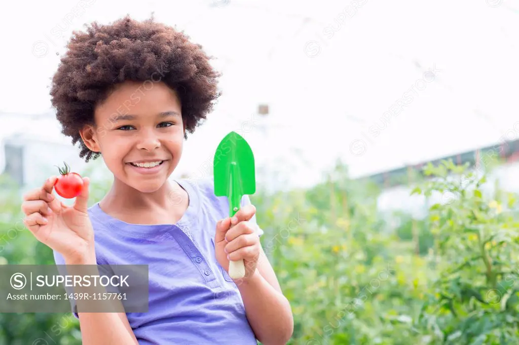 Girl holding tomato and trowel