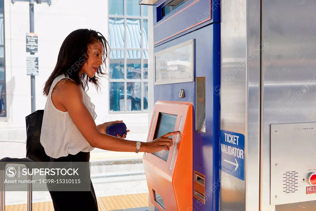Businesswoman buying train ticket at machine