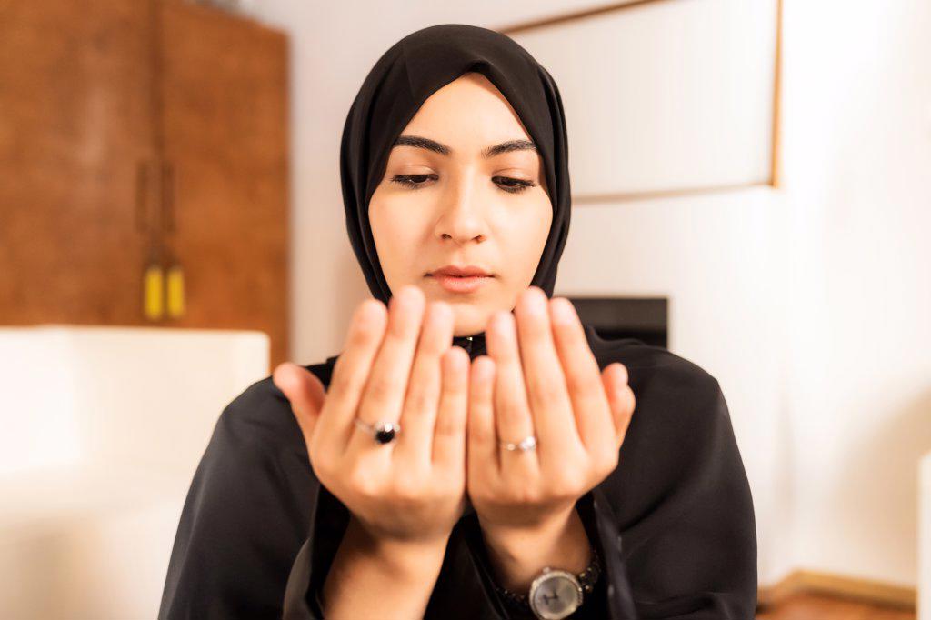 Young muslim woman with hands together during prayer
