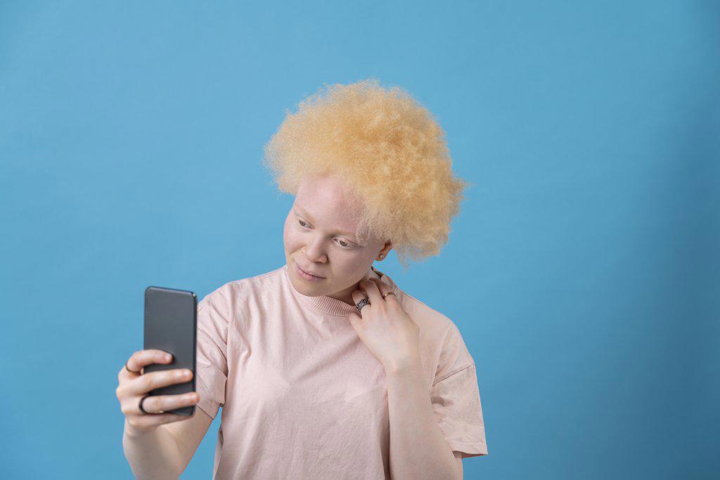 Studio shot of albino woman holding smart phone