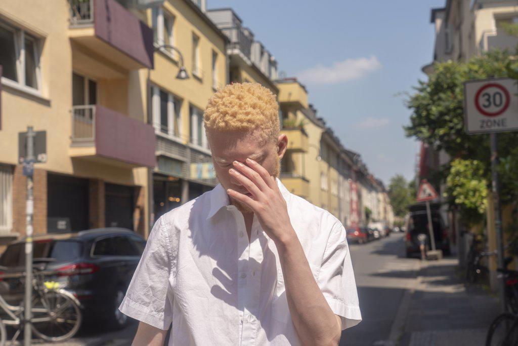 Germany, Cologne, Albino man in white shirt on street