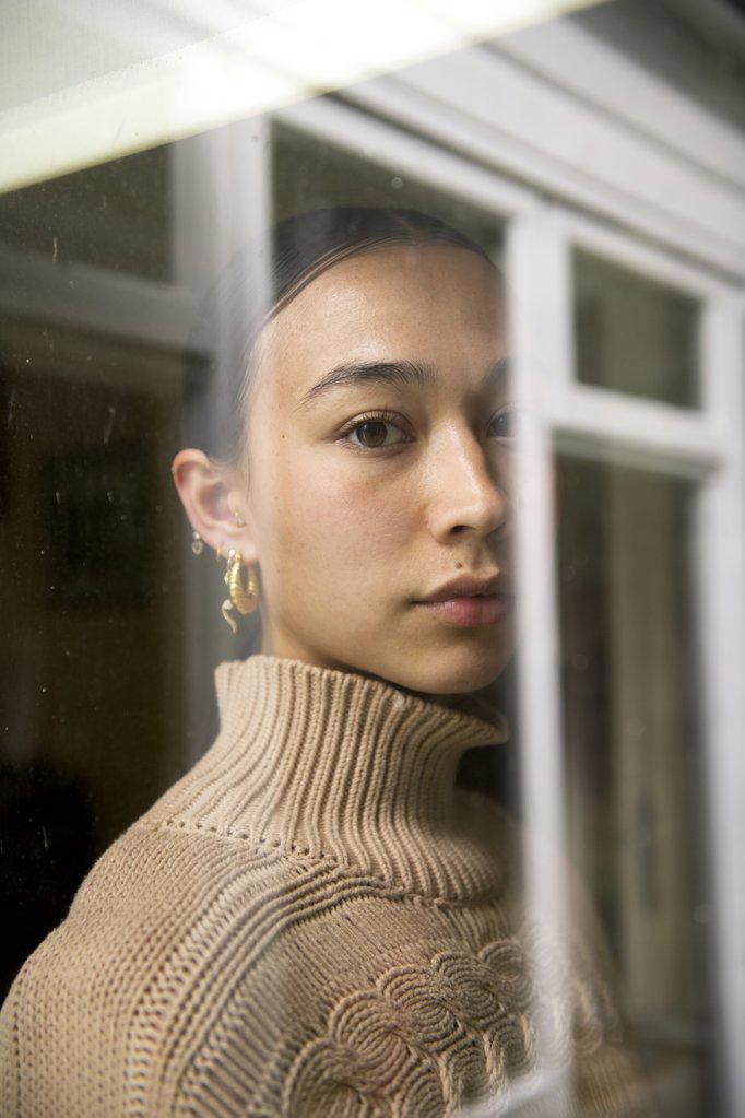 Portrait of young woman reflected in window