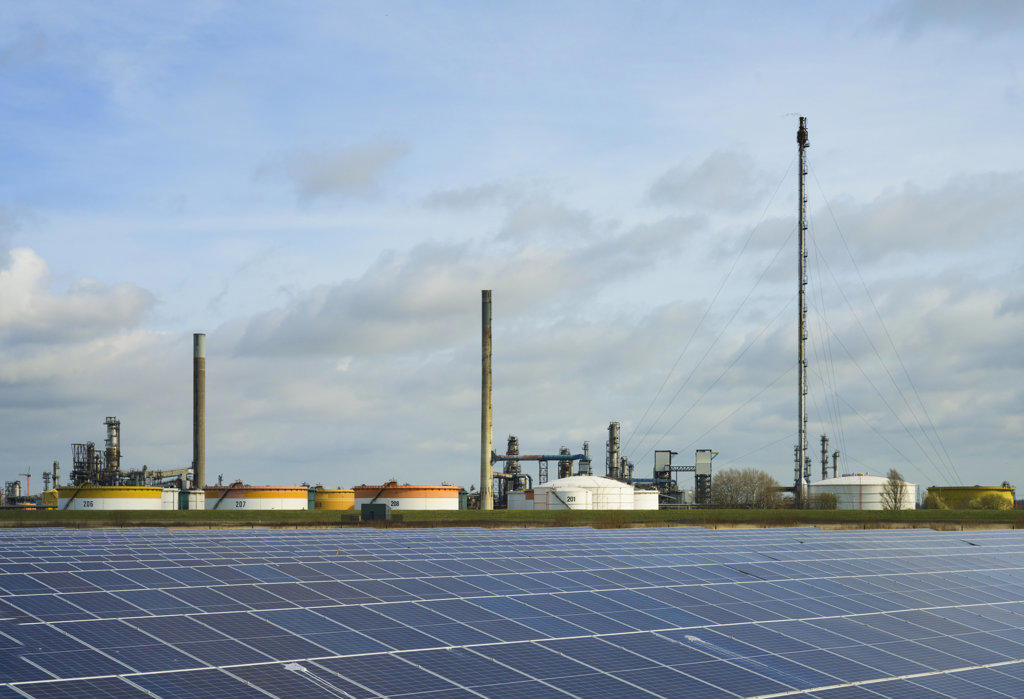 Netherlands, Newly built solar farm in front of oil refinery