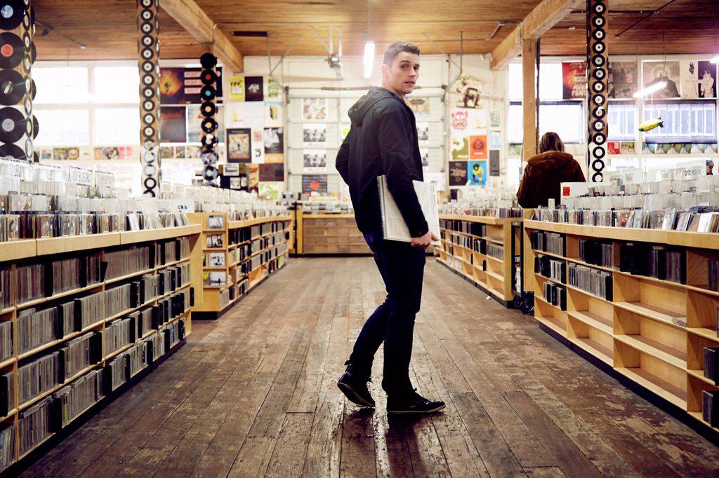 Young man holding vinyl record in music store