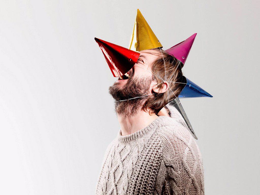 Mid adult man in party hats against white background