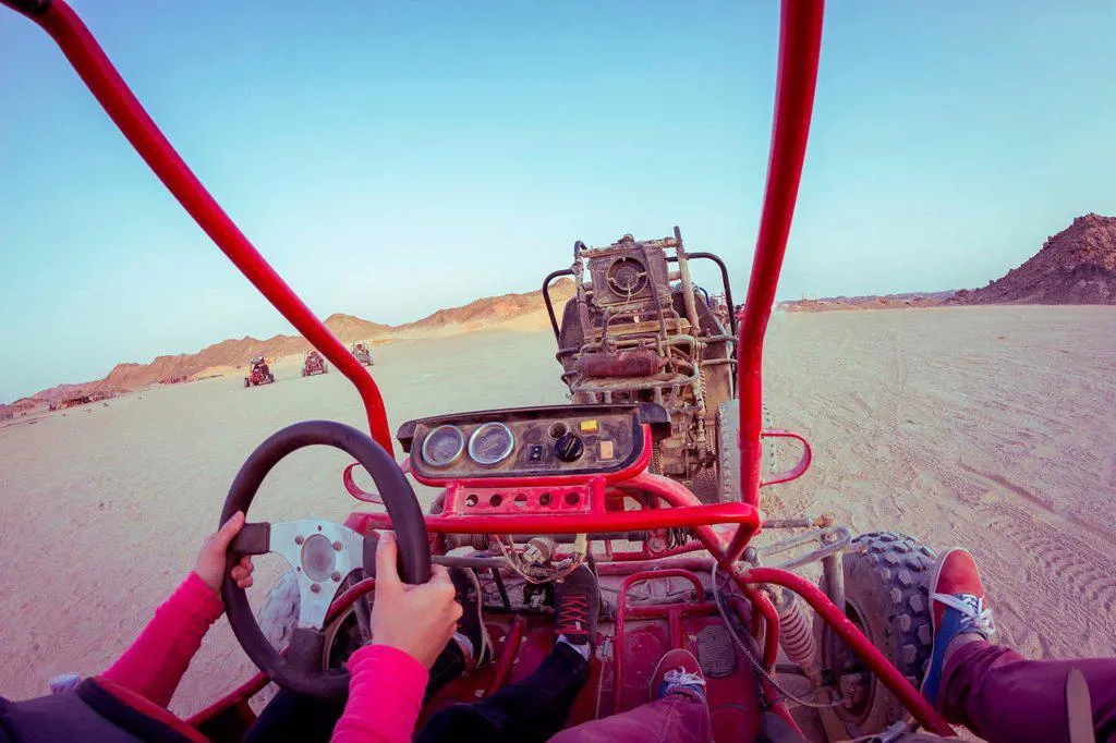 Personal perspective view of two people driving beach buggy in desert, Hurghada, Al Bahr al Ahmar, Egypt