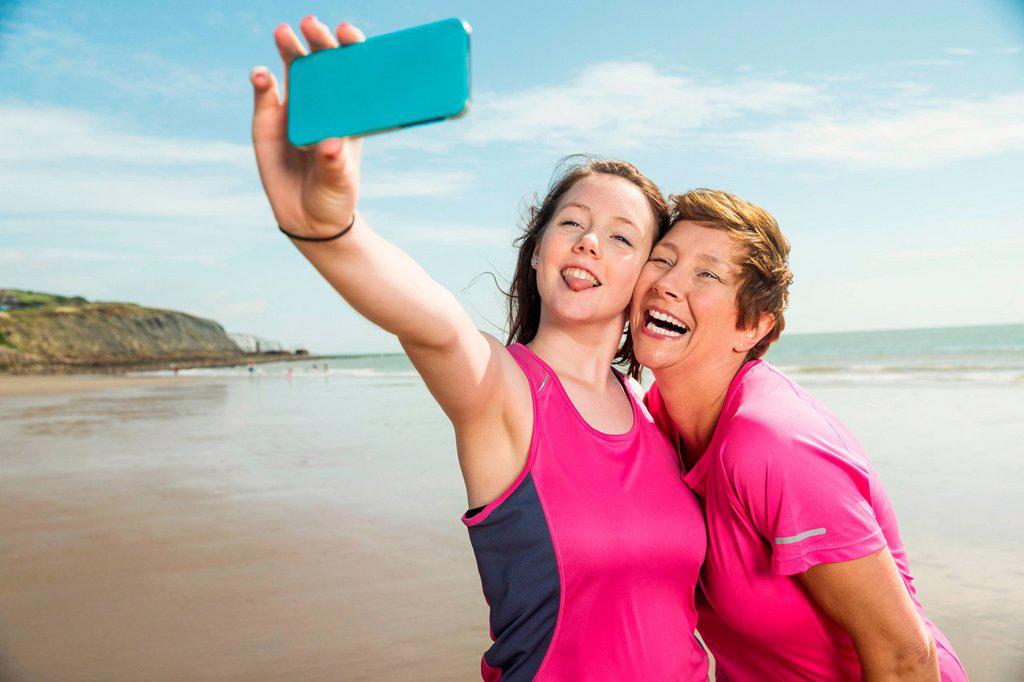 Mother and daughter taking selfie on beach, Folkestone, UK
