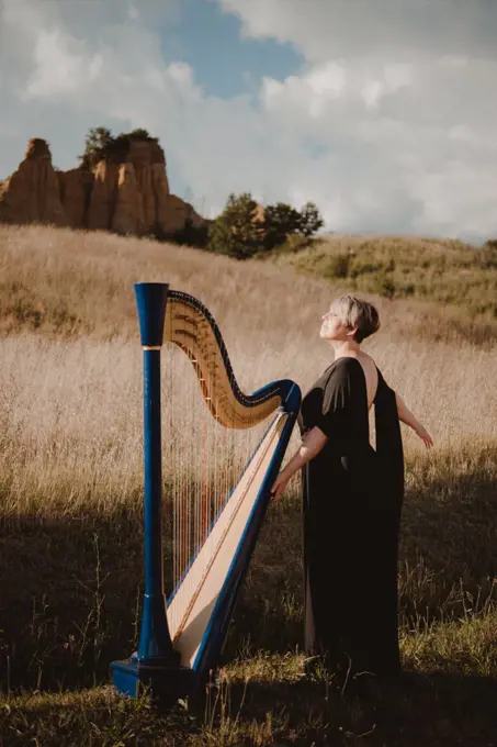 Italy, Tuscany, Firenze, Woman standing in field with harp