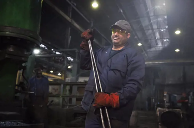 Forge worker primed for action with a set of industrial tongs